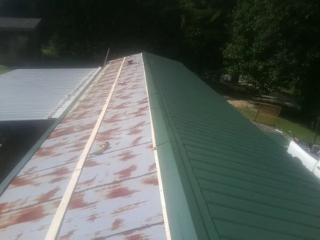 Old rusted panels beside newly installed green metal roofing — Wind Damage Roof Repair by Roofing Brothers in Sheffield