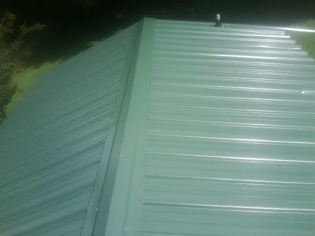 New green metal panels meeting at the ridge of a roof — Flat Roof Repair work by our crew in Sheffield